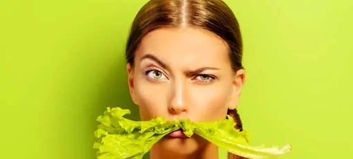 Diätassistentin hält Salatblatt im Mund