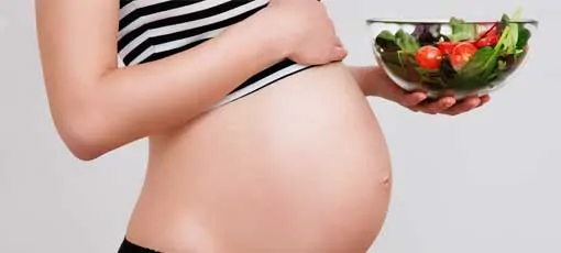 Schwangere Frau hält Salatschüssel