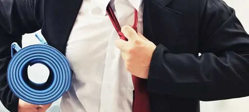 Businessmann öffnet die Krawatte mit Yogamatte unter dem Arm