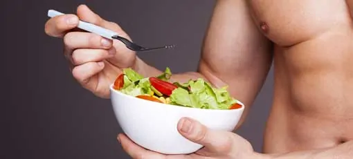 Muskulöser Mann verzehrt Salat