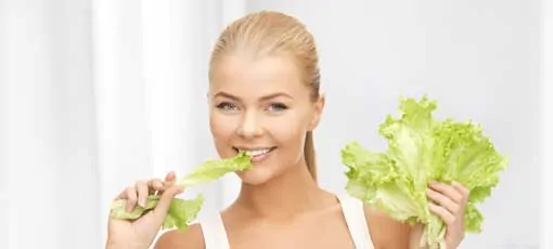 Weiblicher Ernährungscoach knabbert am Salatblatt