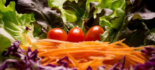 Tomaten und Karottenstreifen liegen auf Salatblättern