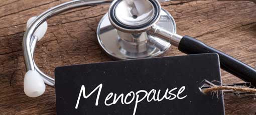Stethoskop auf Holz mit Menopause Wort als medizinisches Konzept