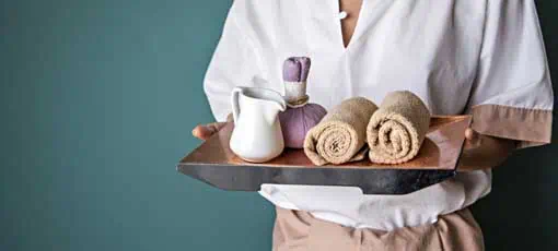 Wellness und Spamanagement - Frau mit gerollten Handtüchern und Massageöl